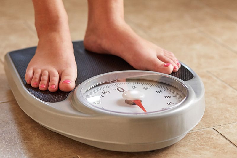 woman checking if she gain weight on weighing scale